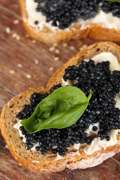 Brotscheiben mit Butter und schwarzem Kaviar auf Holzhintergrund