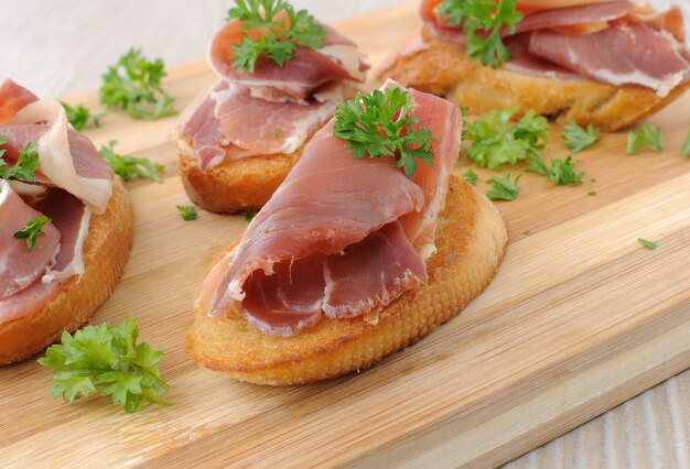 Brotscheiben mit spanischem Jamon Serrano auf einem Holzbrett