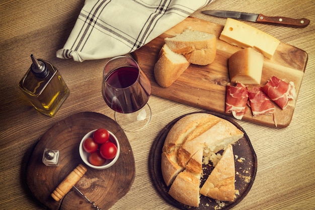 Brotschinkenkäse und ein Glas Wein auf einem Holztisch