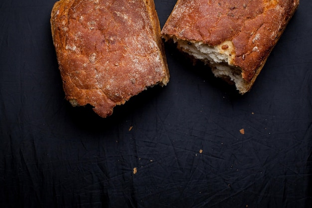 Brotstücke mit Kleie und Samen auf dunklem Hintergrund. Nahaufnahmefoto, weicher Fokus. Gesundes Essen.