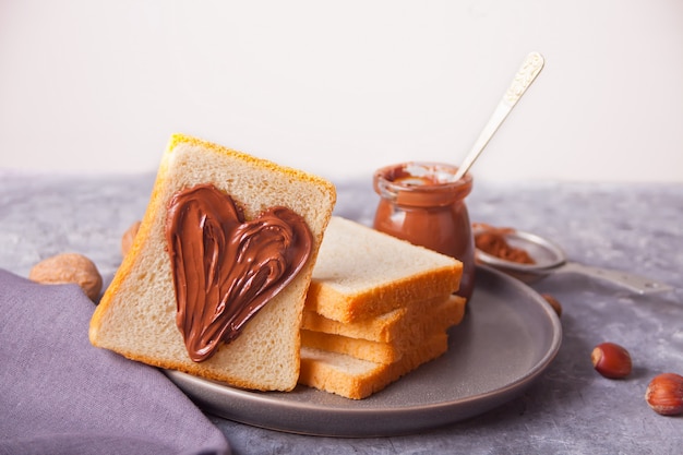 Brottoast mit herzförmiger Schokoladencremebutter, Glas Schokoladencreme