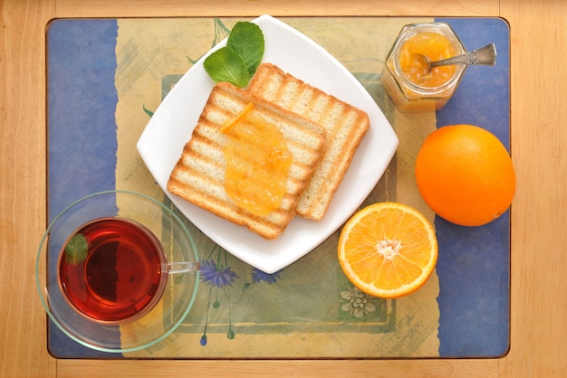 Brottoast mit Orangenmarmelade und schwarzem Tee mit Minze und Orangen