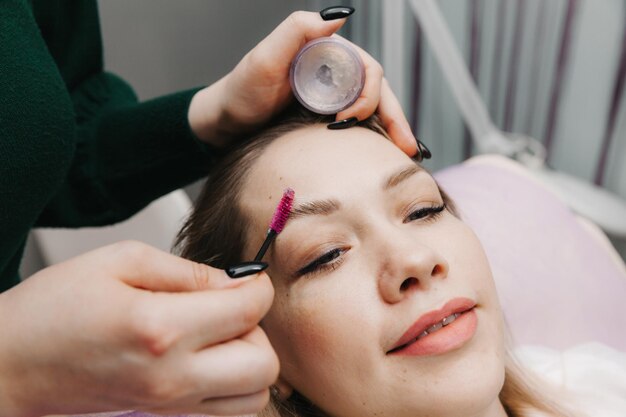 El browist peina las cejas con un cepillo para el cuidado de las cejas en el salón.