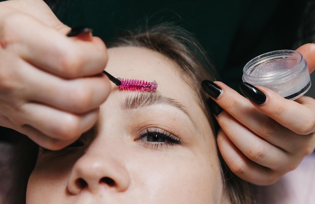 El browist peina las cejas con un cepillo para el cuidado de las cejas en el salón.