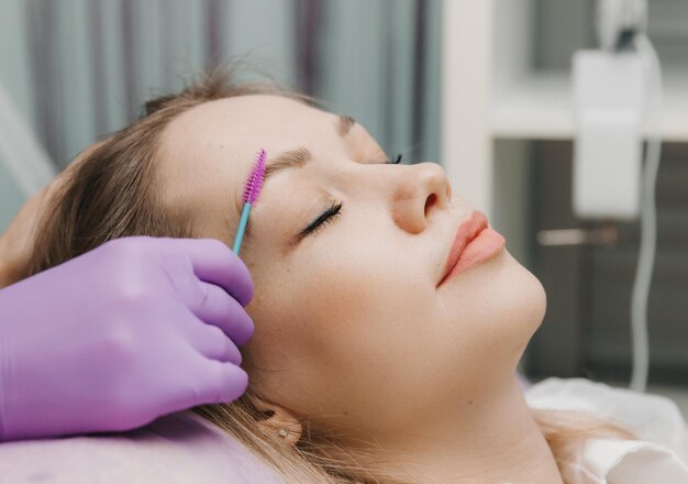 El browist peina las cejas con un cepillo para el cuidado de las cejas en el salón.