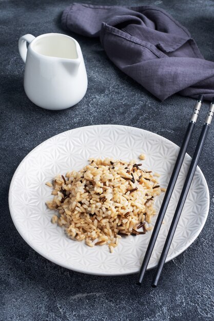 Brown e arroz com casca em um prato com pauzinhos.