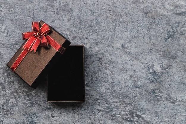 Brown-Geschenkbox und ein goldener Bogen, der offen ist, platziert auf einem grauen Steintisch