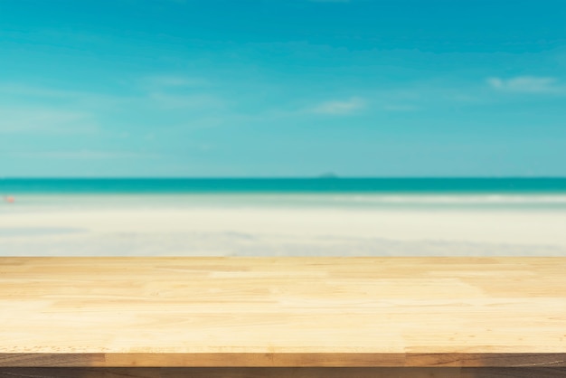 Brown-hölzerne Tischplatte auf unscharfem blauem Meer und weißem Sand setzen Hintergrund auf den Strand.