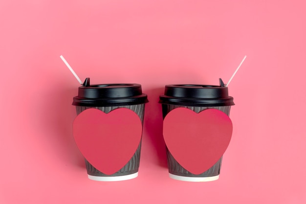 Brown-kaffeetassen, roter herz-förmiger aufkleber auf rosa hintergrund. liebe ist. konzept für kaffeeliebhaber, liebe ist. alles gute zum valentinstag flach legen