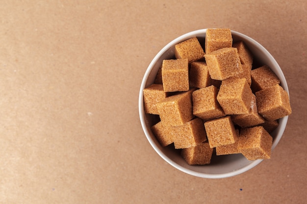 Brown-Rohrzuckerwürfel auf einem hellbraunen Hintergrund