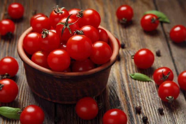 Brown-Schüssel mit Kirschtomaten auf dunklem hölzernem Hintergrund selektiver Fokus Beschneidungspfad eingeschlossen