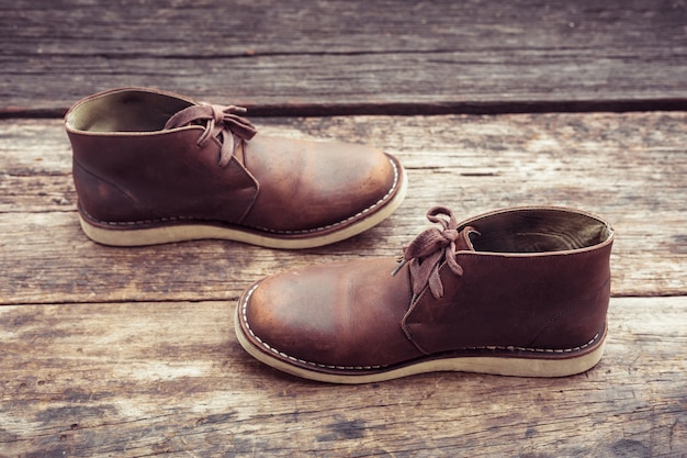 Brown-stilvolle Stiefel auf Holz, Retro- Farbe