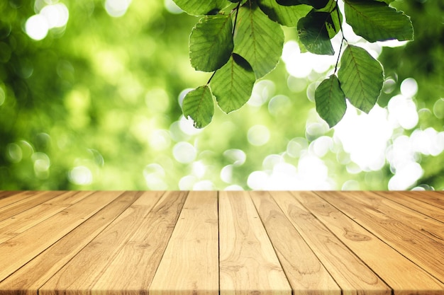 Brown Wood Plank Leerer Tisch mit grünen Blättern und Natur Bokeh im Hintergrund für Display-Produkte