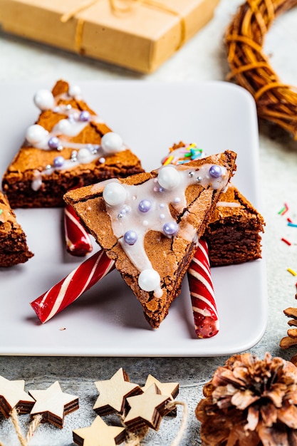 Brownie del árbol de navidad con el bastón de caramelo y la formación de hielo, fondo gris. Concepto de comida navideña.