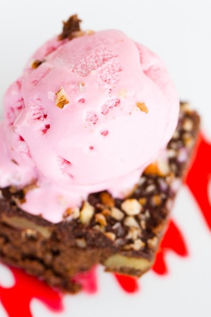 Brownie com molho de cereja e chocolate branco e uma bola de sorvete por cima.