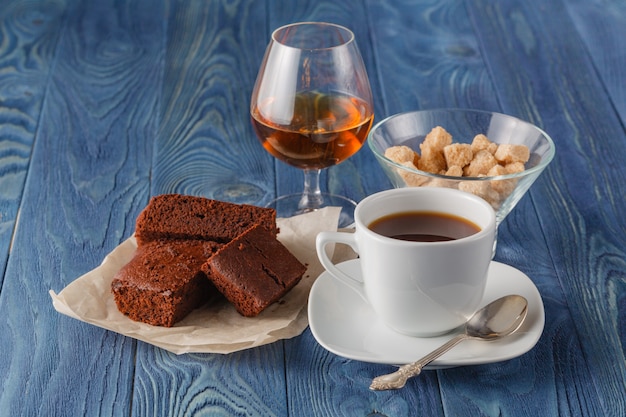 Brownie de chocolate caseiro e um copo de caneca branca na mesa de madeira.