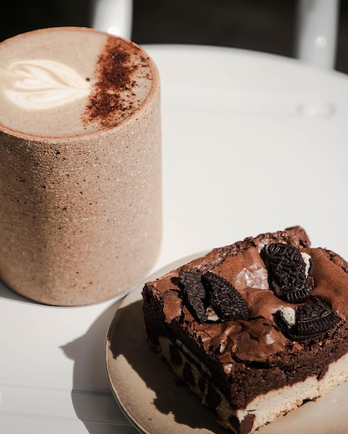 Foto brownie de chocolate com neve e placa de cerâmica de pedaços de chocolate na mesa branca com luz natural