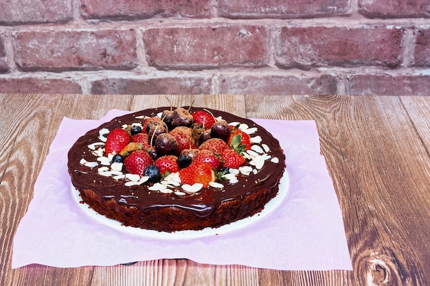 Brownie-Kuchen dekoriert mit roten Beeren auf Holztisch