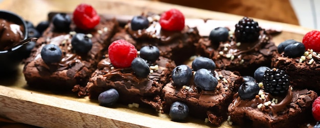 Brownie mit Beeren und Schokolade auf einem Holzbrett Hausgemachte vegane Brownies