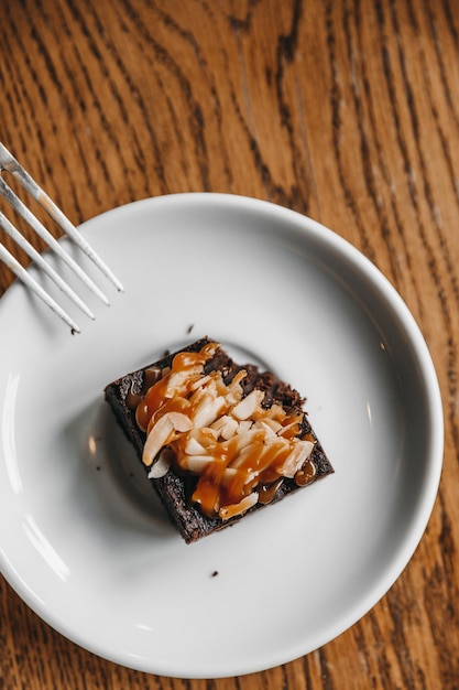 Brownie mit Mandeln wird bereits auf einem Holztisch in einem Café gegessen.