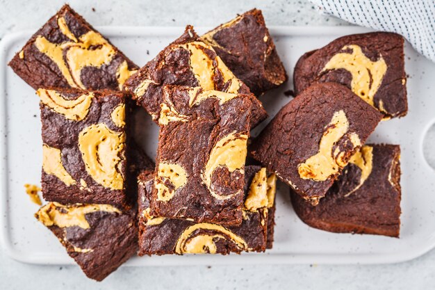 Brownie del vegano con mantequilla de cacahuete en el fondo blanco.