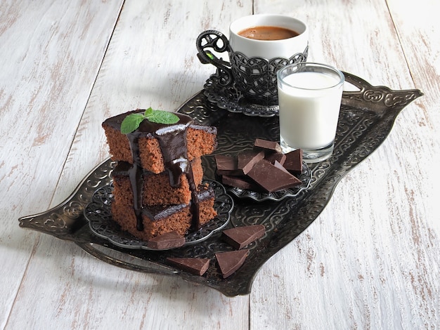 Brownies en una bandeja con leche y una taza de café oriental