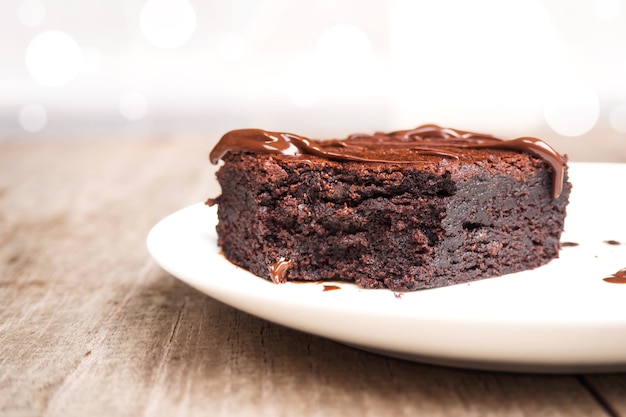 Brownies caseros en la placa blanca. Con relleno de chocolate dulce de azúcar. Sobre fondo de madera.