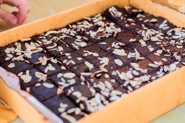 Brownies cubiertos con almendras en una bandeja de papel grande.