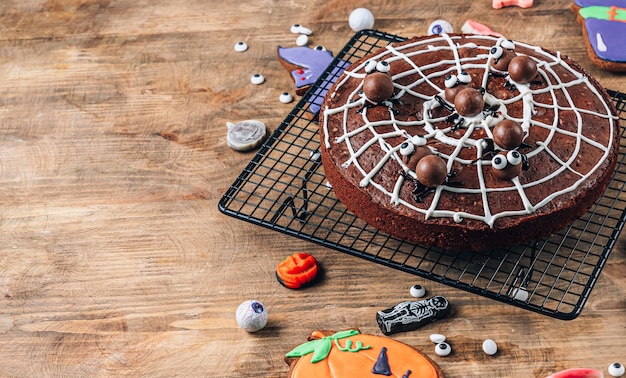 Brownies de telaraña de chocolate con arañas dulces, golosinas caseras para Halloween sobre fondo de madera rústica. Enfoque selectivo con espacio de copia