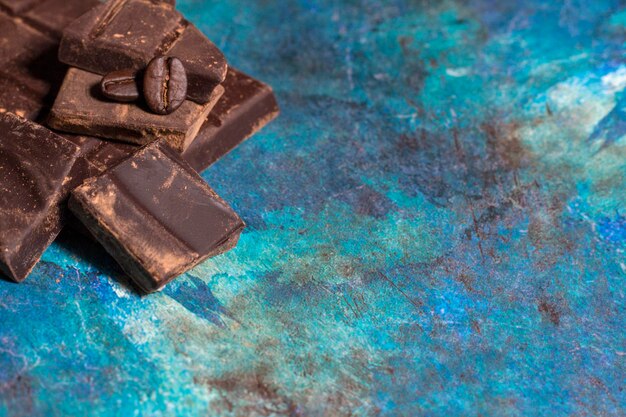 Bruchstücke Schokolade auf blauem abstraktem Hintergrund Ansicht von oben