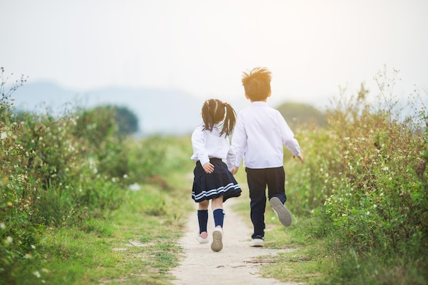 Bruder, der die Hand der Schwester hält, die auf dem Feld läuft