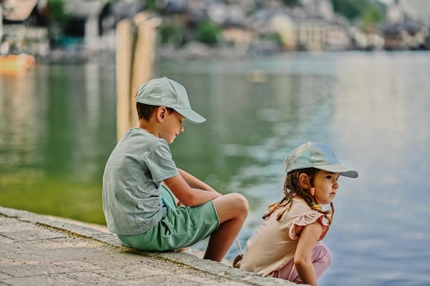 Bruder mit Schwester sitzen in der Nähe des Alpensees in Hallstatt Österreich