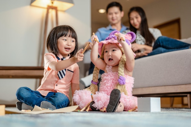 Bruder spielte mit seiner Schwester Er hob die Hand und lachte die kleine Schwester auf dem Teppich aus