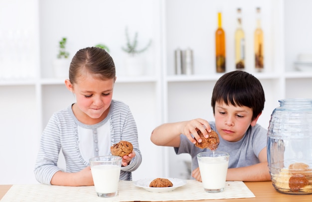 Bruder und Schwester, die Plätzchen essen und Milch trinken