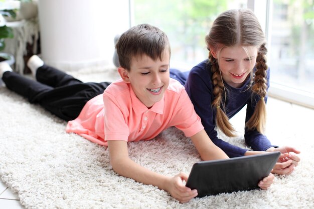 Bruder und Schwester, die zu Hause ein digitales Tablet auf dem Boden verwenden