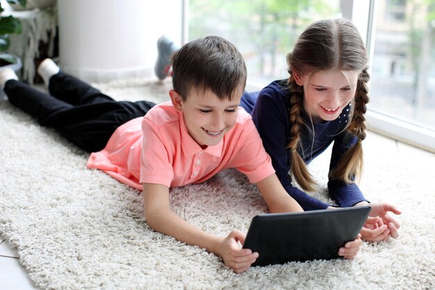 Bruder und Schwester, die zu Hause ein digitales Tablet auf dem Boden verwenden