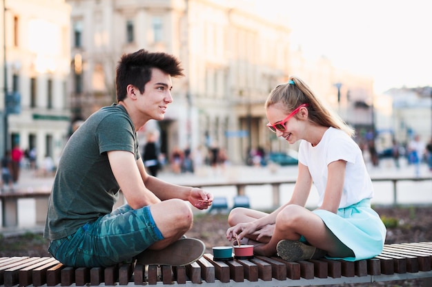 Bruder und Schwester essen Eis, während sie in der Stadt sitzen