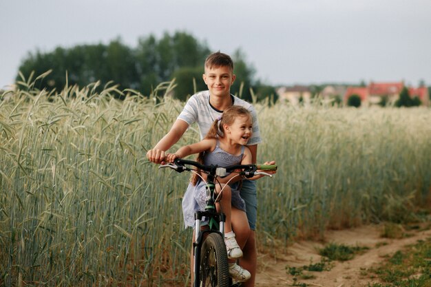 Bruder und Schwester fahren Fahrrad auf einem Weizenfeld