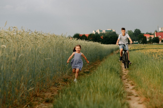 Bruder und Schwester fahren Fahrrad auf einem Weizenfeld