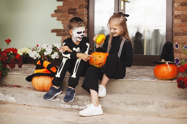 Bruder und Schwester feiern Halloween auf der Straße in der Nähe des Hauses in Kostümen