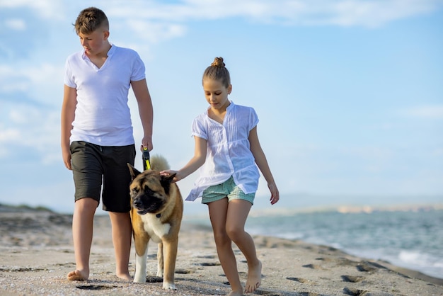 Bruder und Schwester gehen spazieren und mit Hund der Rasse Akita Inu entlang der Küste entlang des Schwarzen Meeres