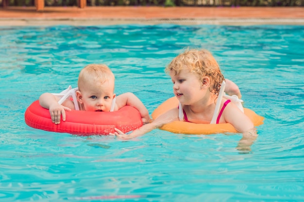 Bruder und Schwester haben Spaß im Pool in aufblasbaren Kreisen