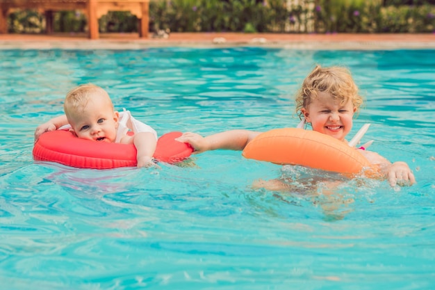 Bruder und Schwester haben Spaß im Pool in aufblasbaren Kreisen