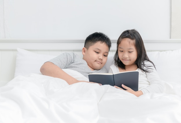 Bruder und Schwester lasen zusammen Buch auf Bett