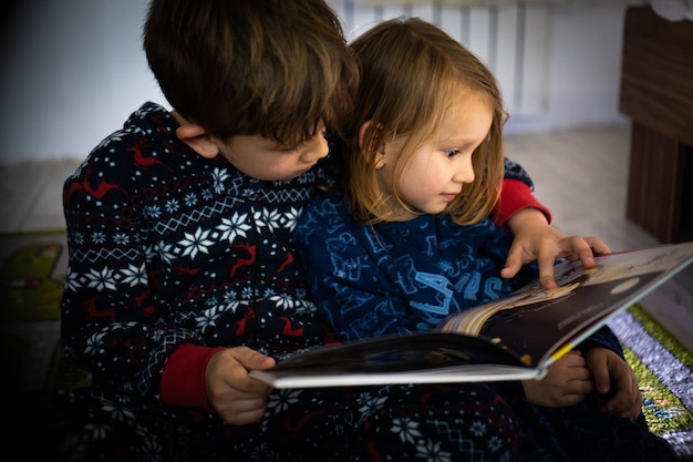 Bruder und Schwester lesen Buch im Pyjama barfuß Abendschlaf Familie