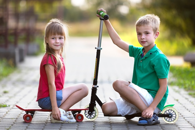 Bruder und Schwester mit Roller und Skateboard