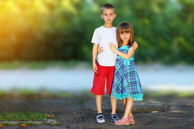 Bruder und Schwester mit zwei kleinen Kindern zusammen. Mädchen im Kleid, das Jungen umarmt. Familienbeziehungen Konzept.