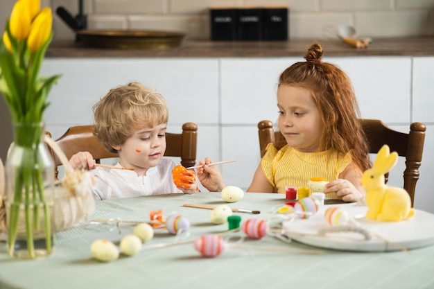 Bruder und Schwester sitzen am Küchentisch und bemalen Ostereier