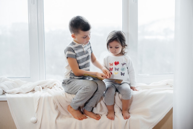 Bruder und Schwester sitzen auf der Fensterbank