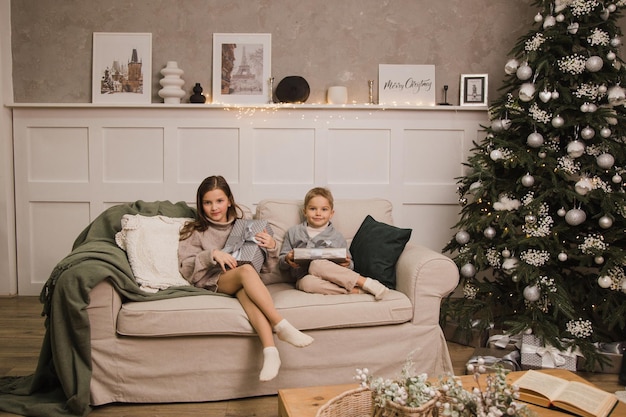 Bruder und Schwester sitzen mit Geschenken zu Hause auf der Couch. Neujahrskonzept